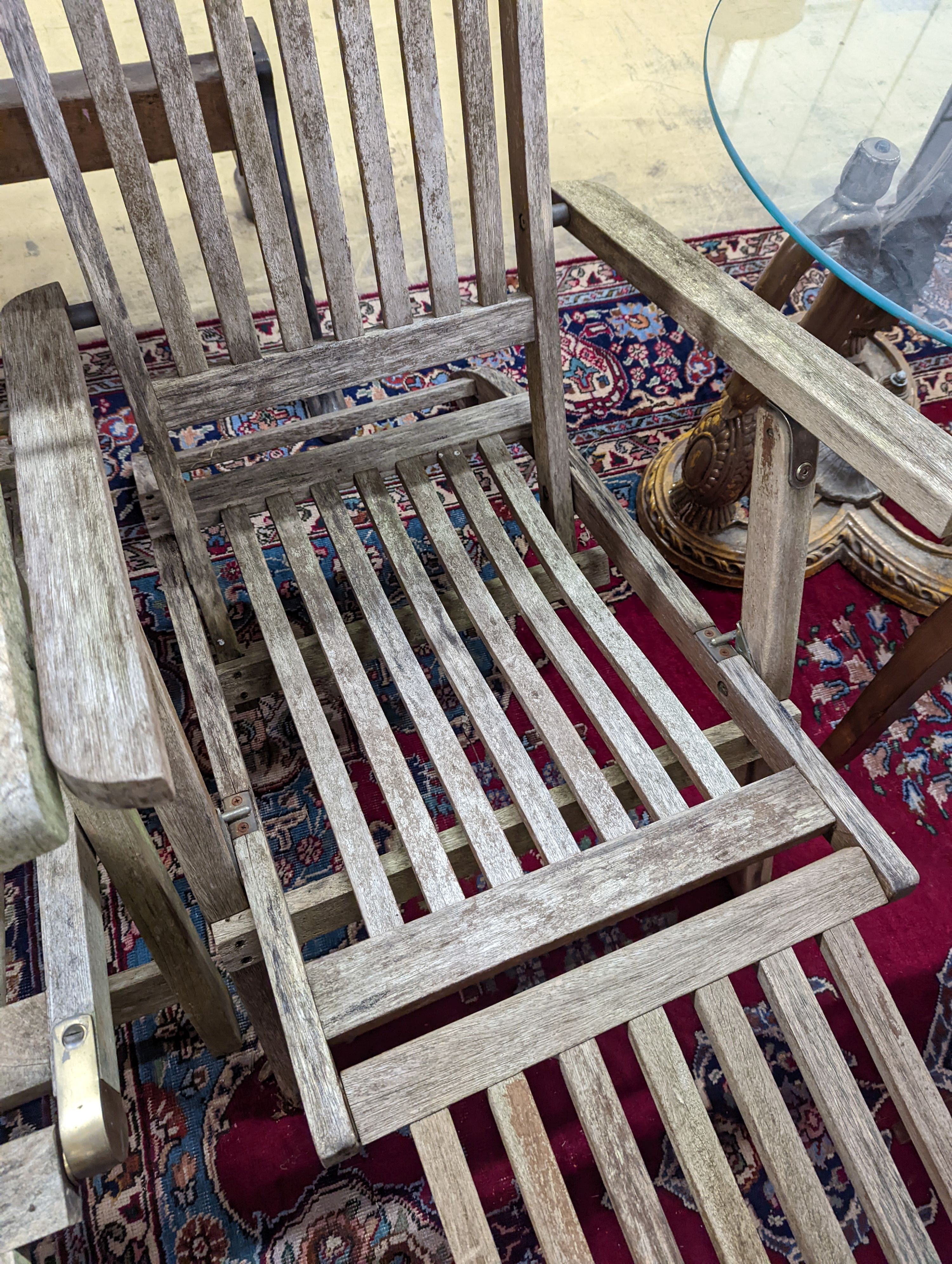 Two weathered teak garden steamer chairs. Heights for both chairs, 102cm and 88cm.